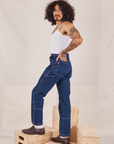 Side view of Carpenter Jeans in Dark Wash and vintage off-white Cami worn by Jesse