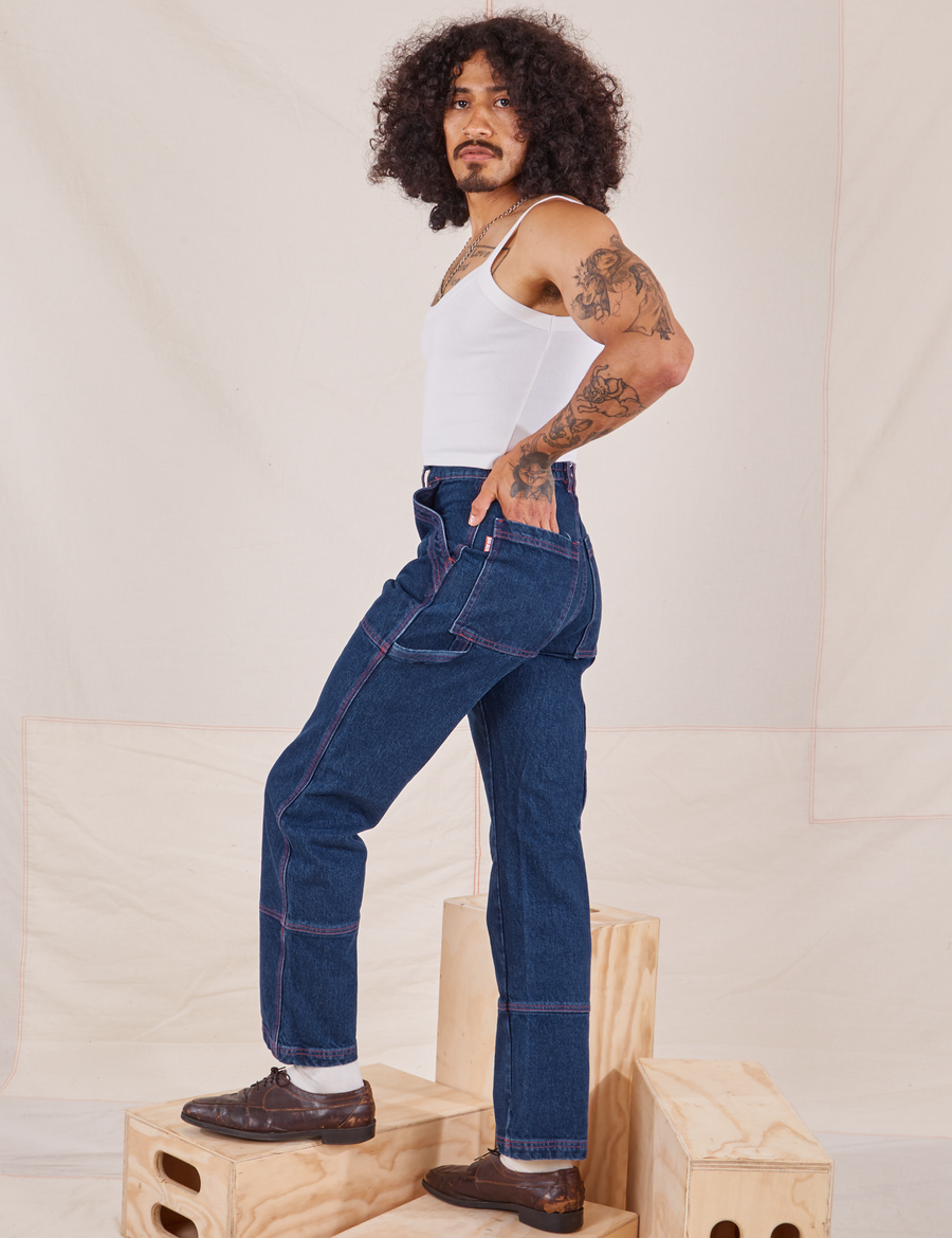 Side view of Carpenter Jeans in Dark Wash and vintage off-white Cami worn by Jesse