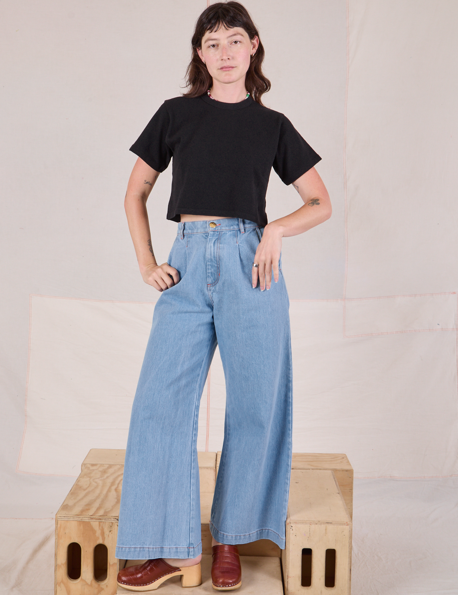 Alex is wearing Cropped Burly Tee in Basic Black and light wash Indigo Wide Leg Denim Trousers