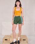 Alex is 5'8" and wearing P Painted Stripe Easy Shorts in Dark Emerald Green paired with a golden yellow Cropped Tank