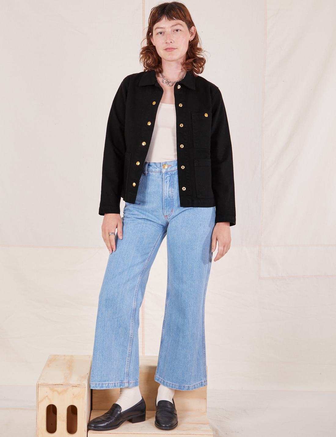 Alex is wearing Denim Work Jacket in Basic Black with vintage off-white Tank Top underneath paired with light wash Sailor Jeans