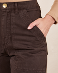 Front pocket close up of Work Pants in Espresso Brown. Worn by Soraya with her hand in the pocket