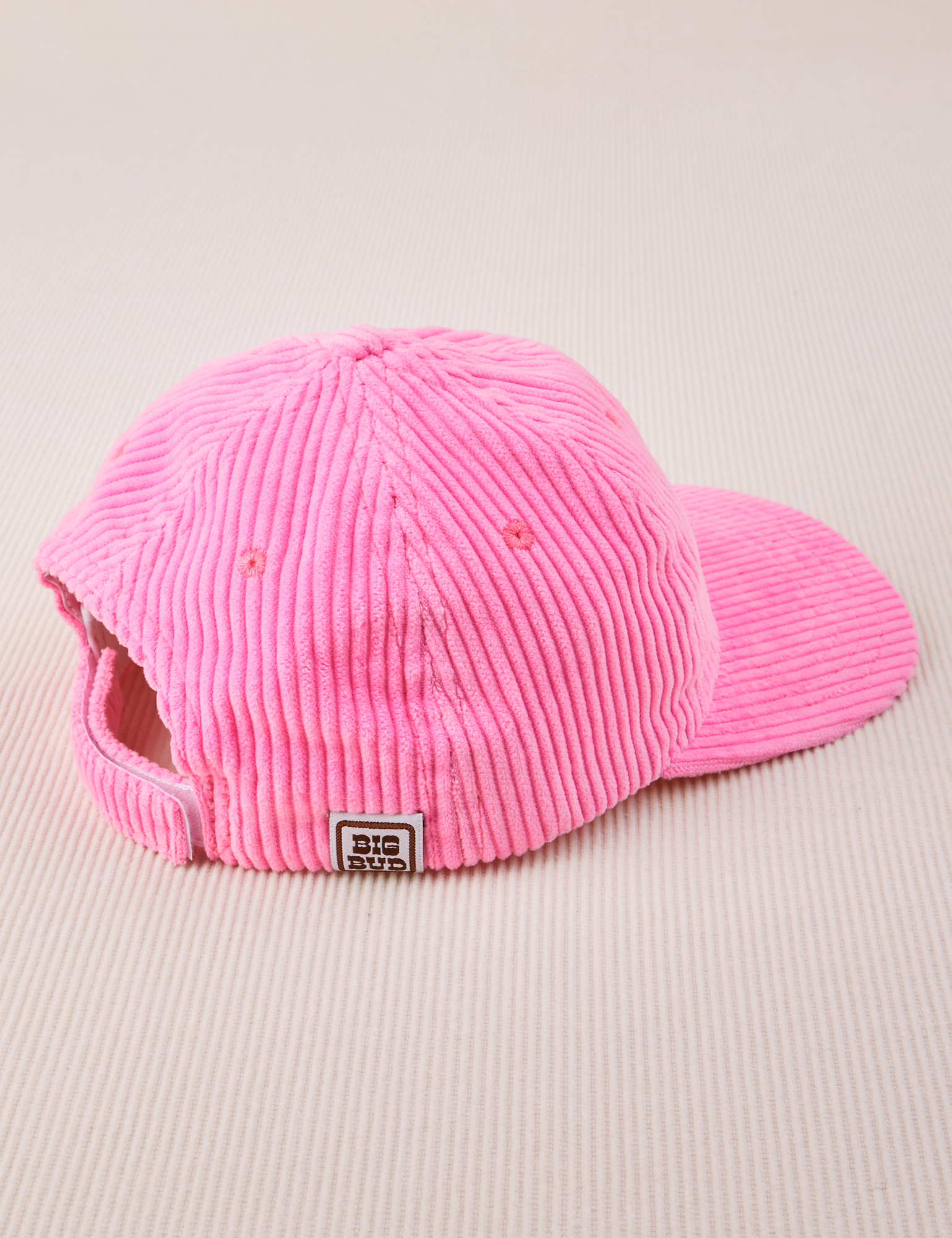 Side view of Dugout Corduroy Hat in Bubblegum Pink. Big Bud tag sewn on the side.