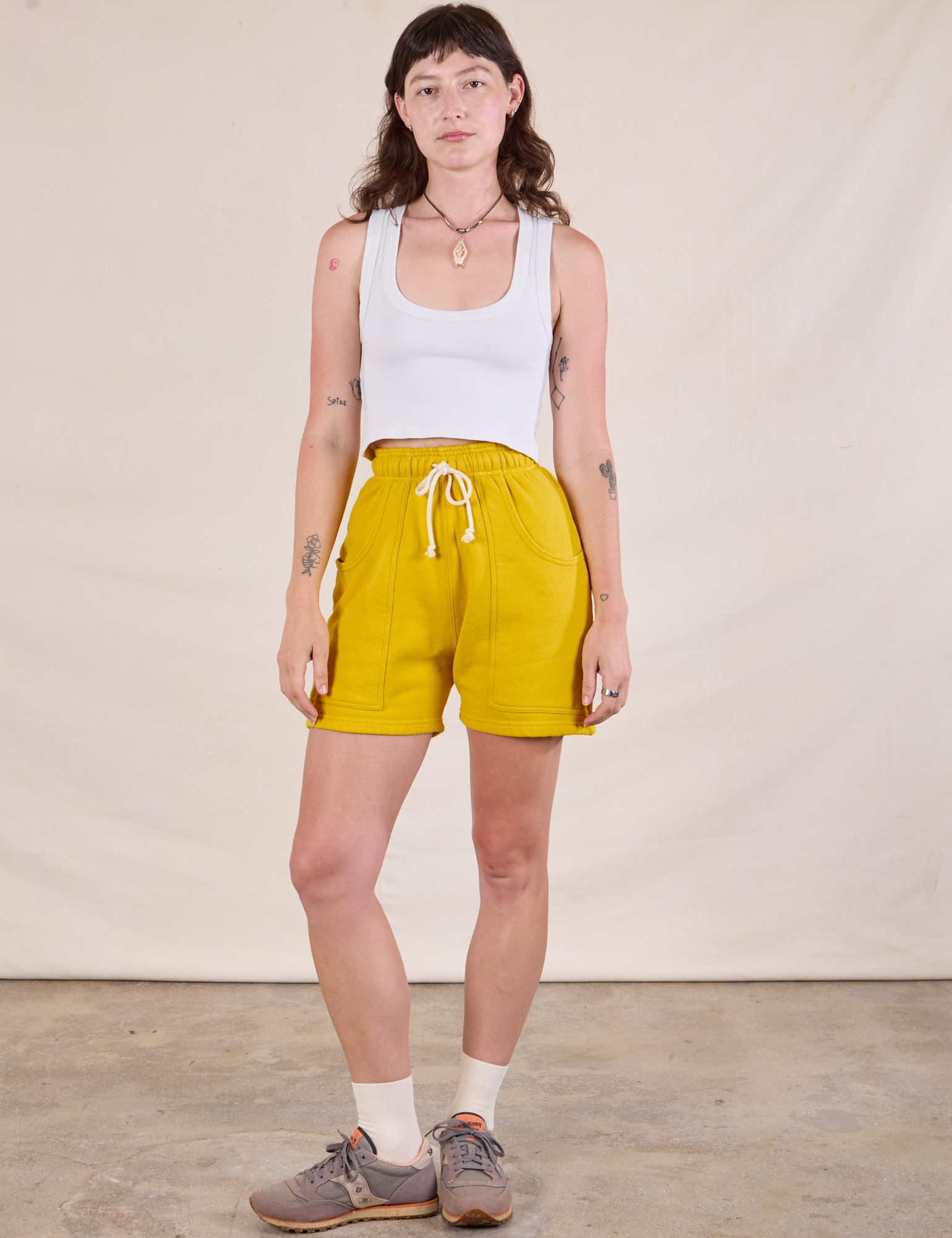 Alex is 5'8" and wearing XXS Heavyweight Sweat Shorts in Golden Yellow paired with a Cropped Tank in Vintage Tee Off-White