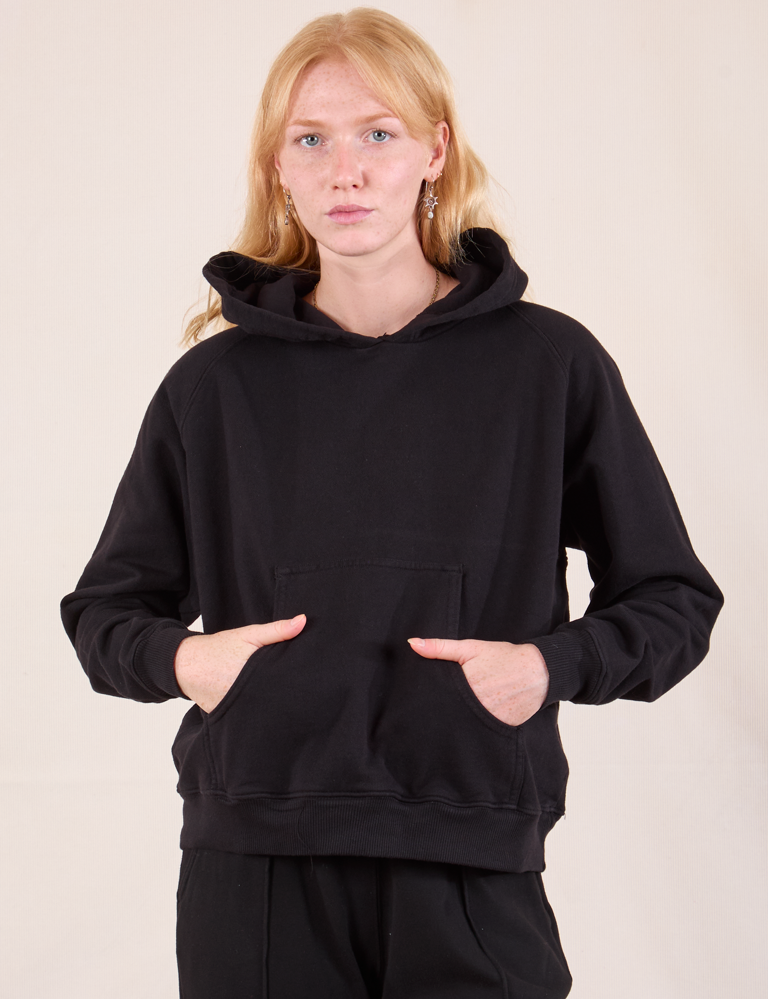 Margaret is wearing Oversized Hoodie in Basic Black and has her hands tucked into the front pocket.