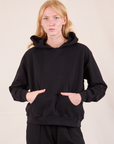 Margaret is wearing Oversized Hoodie in Basic Black and has her hands tucked into the front pocket.