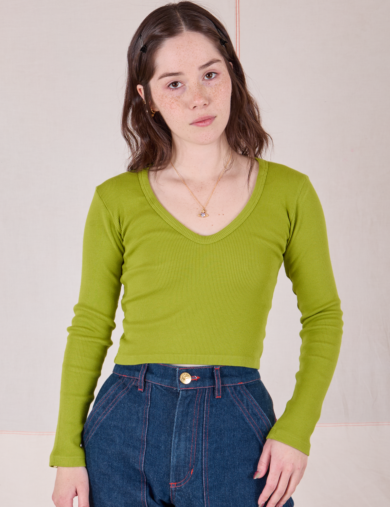 Hana is 5'3" and wearing P Long Sleeve V-Neck Tee in Gross Green