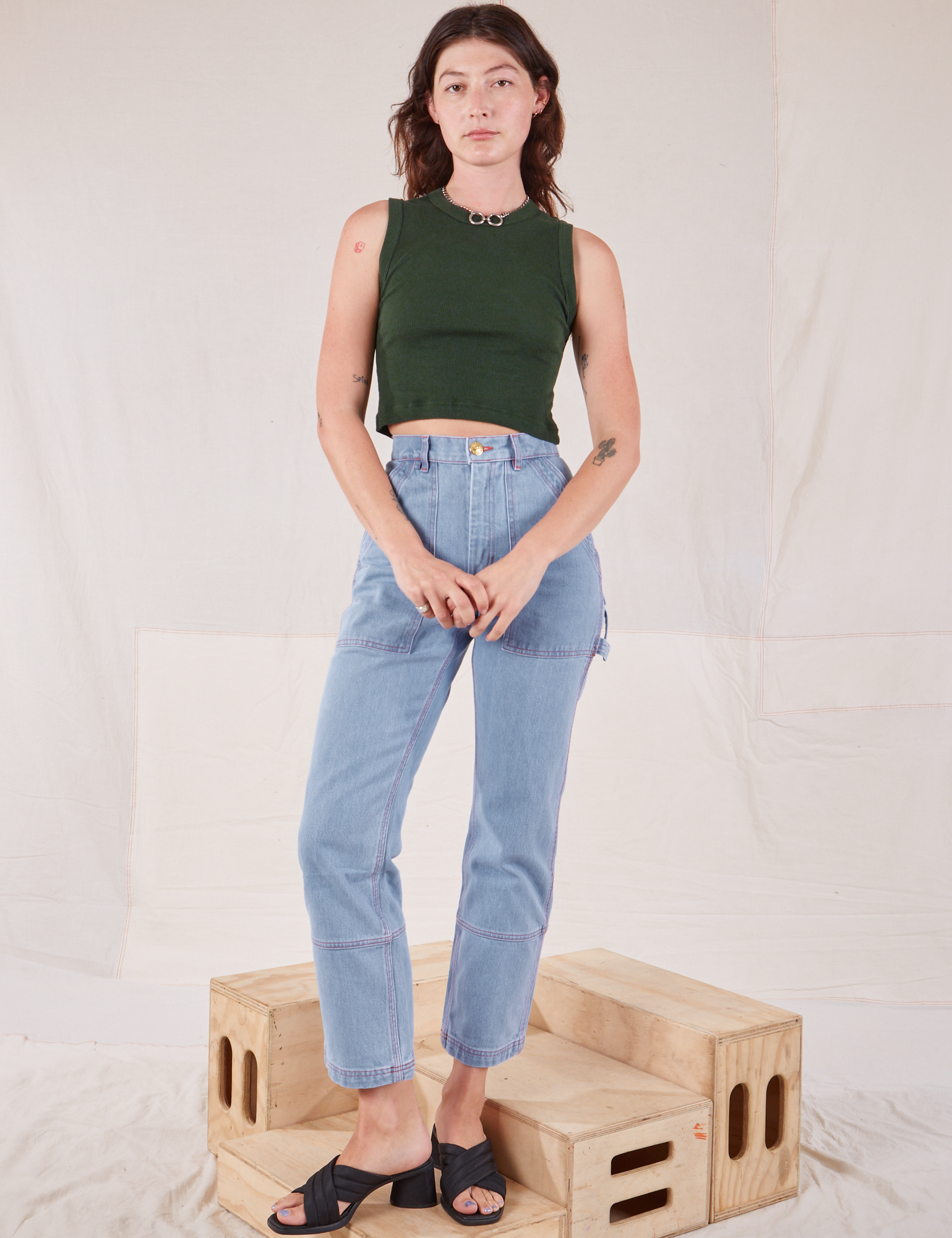 Alex is wearing Muscle Tee in Swamp Green and light wash Carpenter Jeans