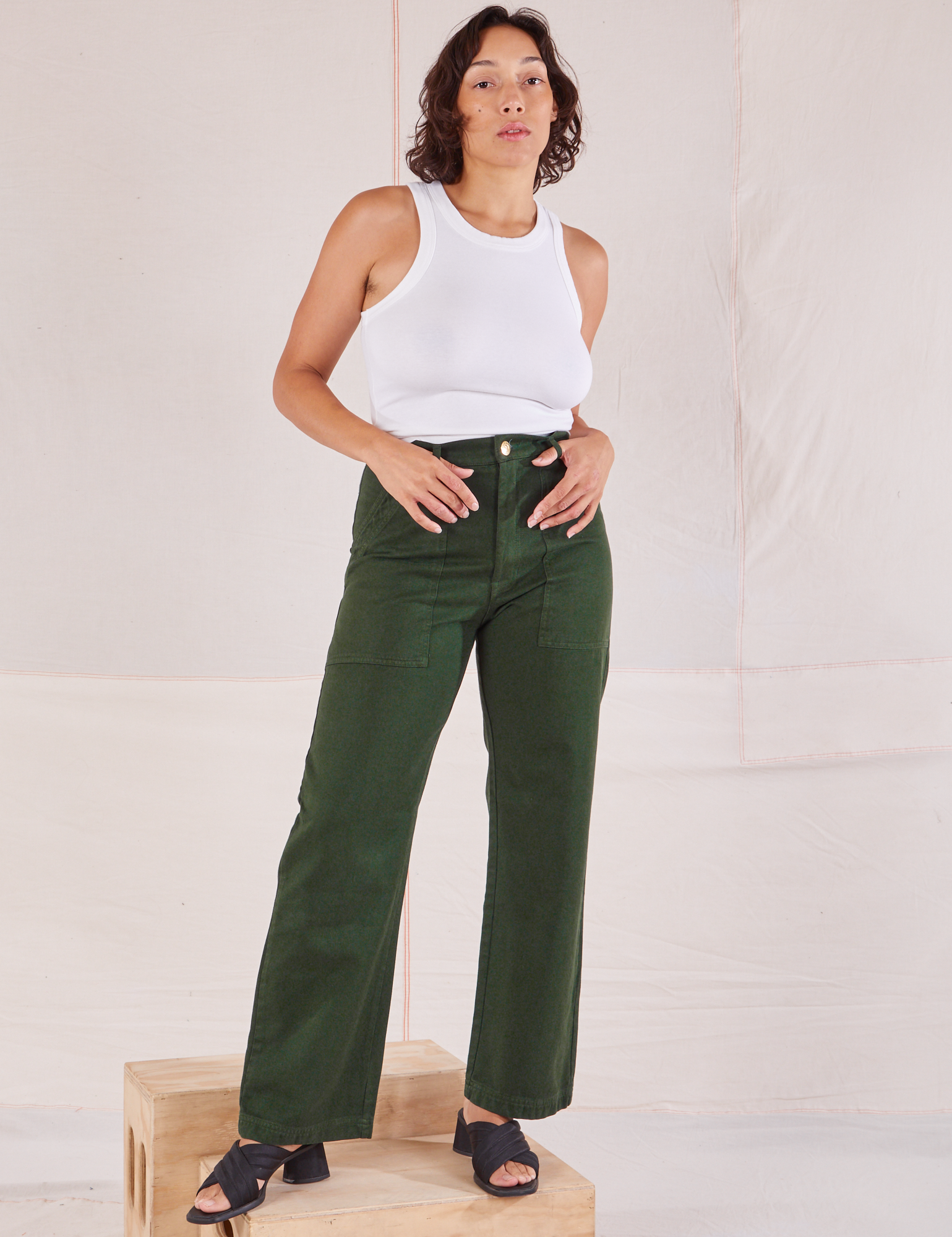 Tiara is wearing Organic Work Pants in Swamp Green and Racerback Tank in vintage tee off-white