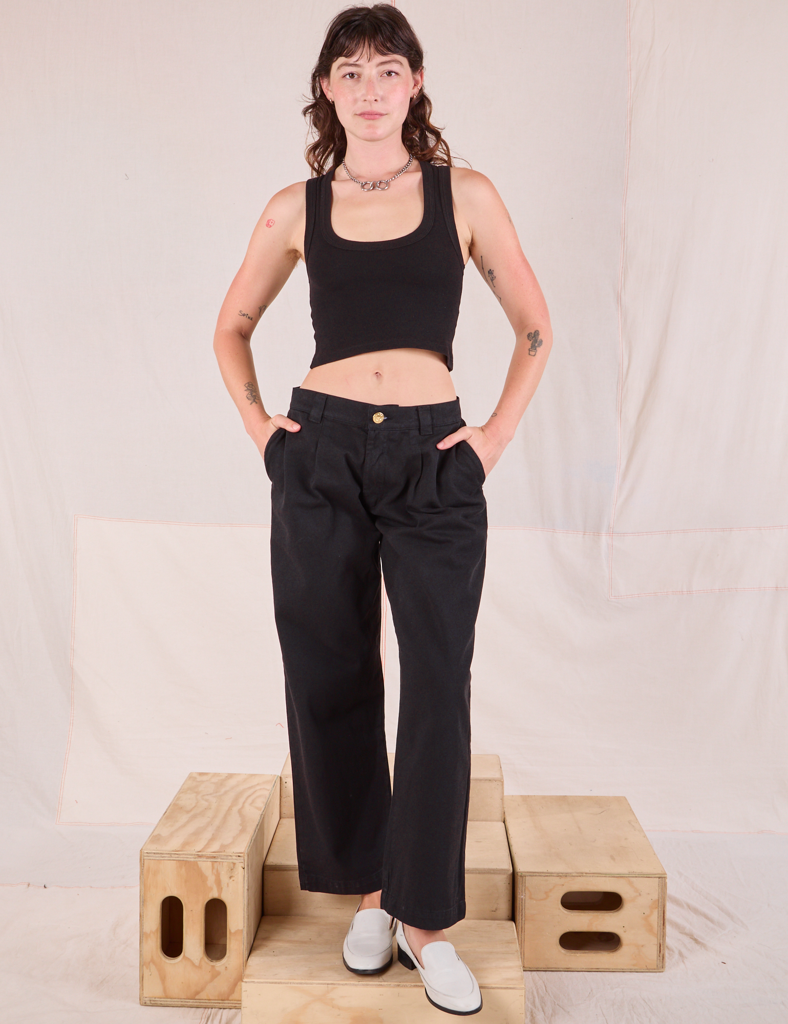 Alex is wearing Mid-Rise Pleated Trousers in Basic Black and black Cropped Tank