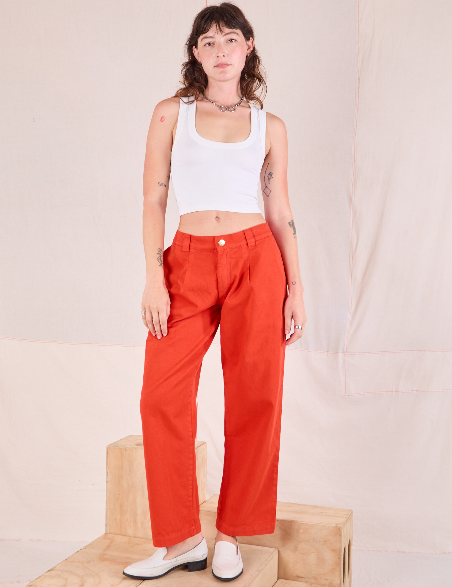 Alex is wearing Mid-Rise Pleated Trousers in Chili Red and Cropped Tank in Vintage Tee Off-White