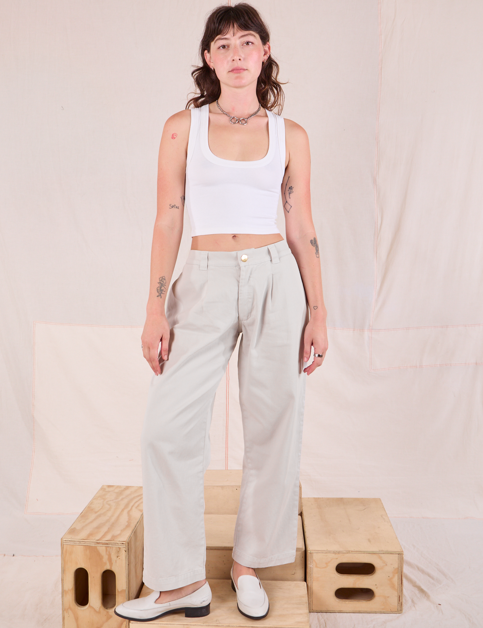 Alex is wearing Mid-Rise Pleated Trousers in Stone White and Cropped Tank in vintage tee off-white