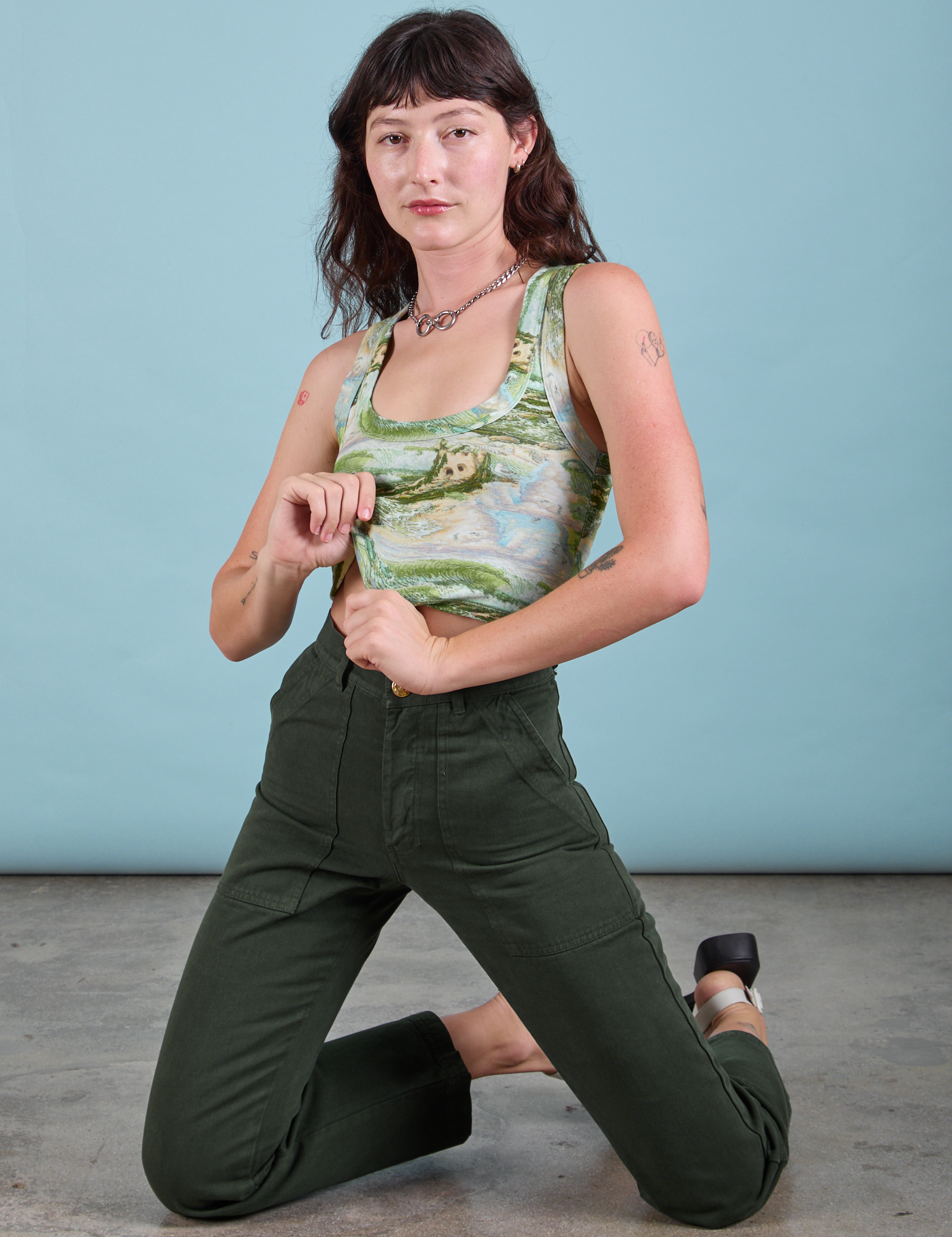 Alex is kneeling and wearing Cropped Tank Top in Ocean and Sky and swamp green Work Pants
