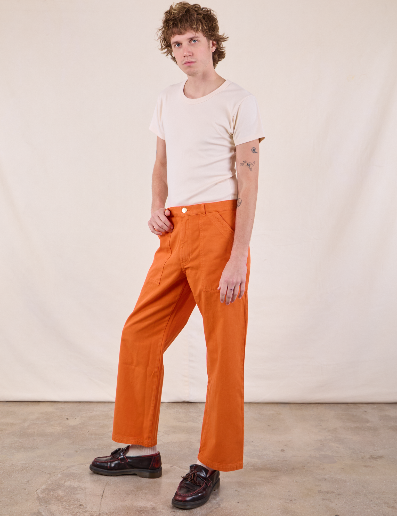 Angled front view of Work Pants in Construction Orange and Burly Tee in Vintage Tee Off-White on Quinn