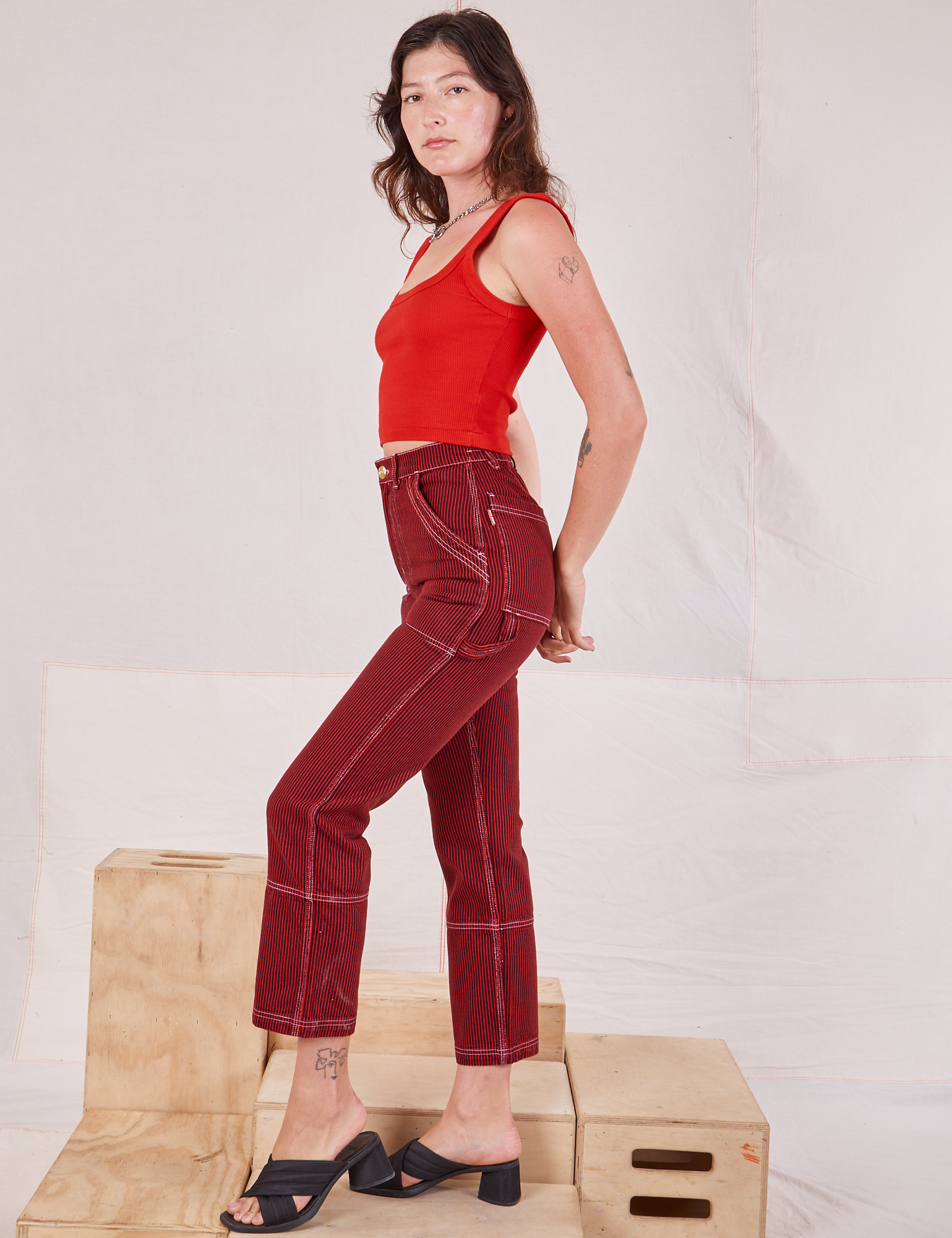 Side view of Railroad Carpenter Jeans in Mustang Red and mustang red Square Neck Tank on Alex