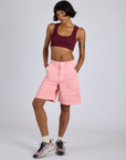 Kira is 5’10” and wearing XS Longline Work Shorts in Baby Pink paired with red wine Mini Tank