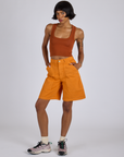 Kira is wearing Longline Work Shorts in Creamsicle Orange and burnt terracotta Cropped Tank