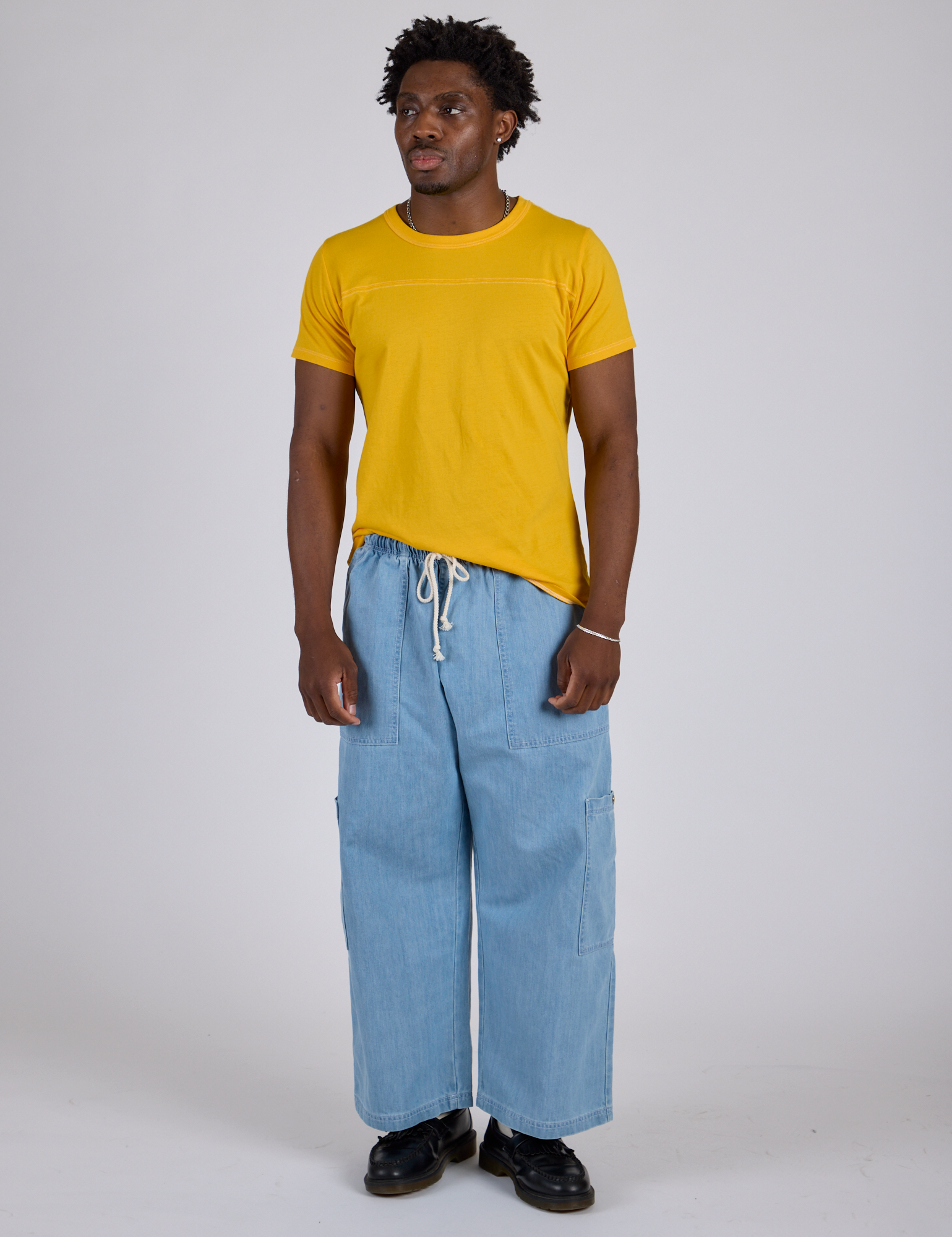 Isaac is wearing Jr. Varsity Tee in Sunshine Yellow and light wash Denim Drop Pocket Pants