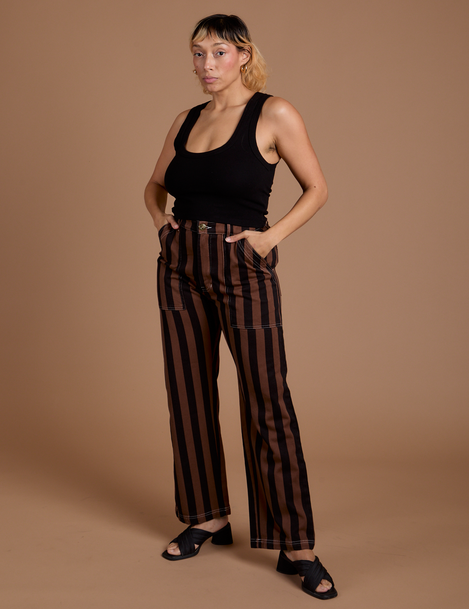 Tiara is 5’4” and wearing S Black Stripe Work Pants in Fudgesicle Brown paired with black Cropped Tank