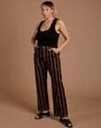 Tiara is 5’4” and wearing S Black Stripe Work Pants in Fudgesicle Brown paired with black Cropped Tank