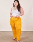 Ashley is 5'7" and wearing XL Cropped Rolled Cuff Sweatpants in Mustard Yellow paired with vintage off-white Cropped Tank Top