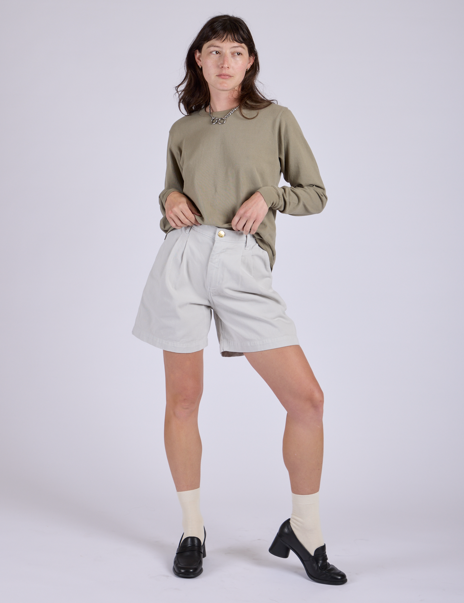 Alex is 5’8” and wearing XXS Pleated Trouser Shorts in Dishwater White paired with khaki grey Long Sleeve Burly Tee