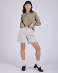 Alex is 5’8” and wearing XXS Pleated Trouser Shorts in Dishwater White paired with khaki grey Long Sleeve Burly Tee