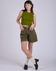 Alex is 5’8” and wearing XXS Pleated Trouser Shorts in Surplus Green paired with summer olive Muscle Tee