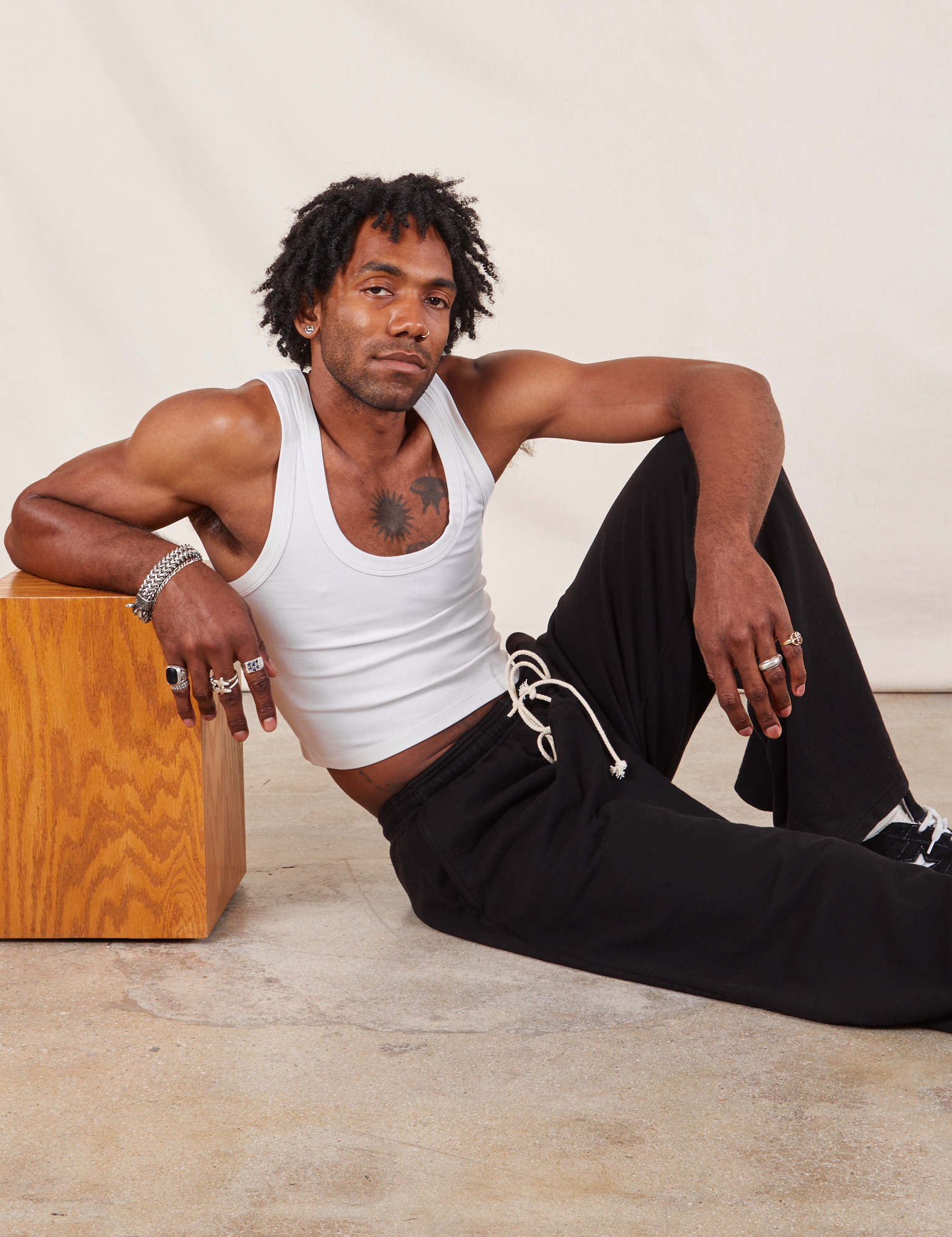 Jerrod is wearing Wide Leg Sweat Pants in Basic Black and Cropped Tank in vintage tee off-white