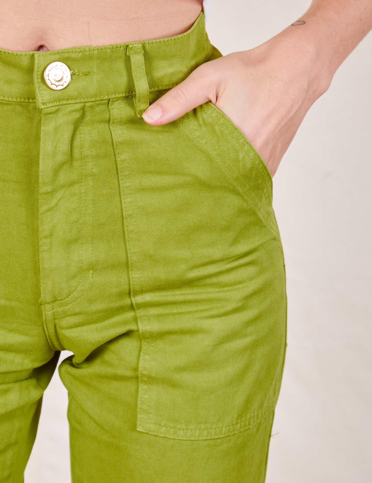 Work Pants in Gross Green front pocket close up. Alex has her hand in the pocket.