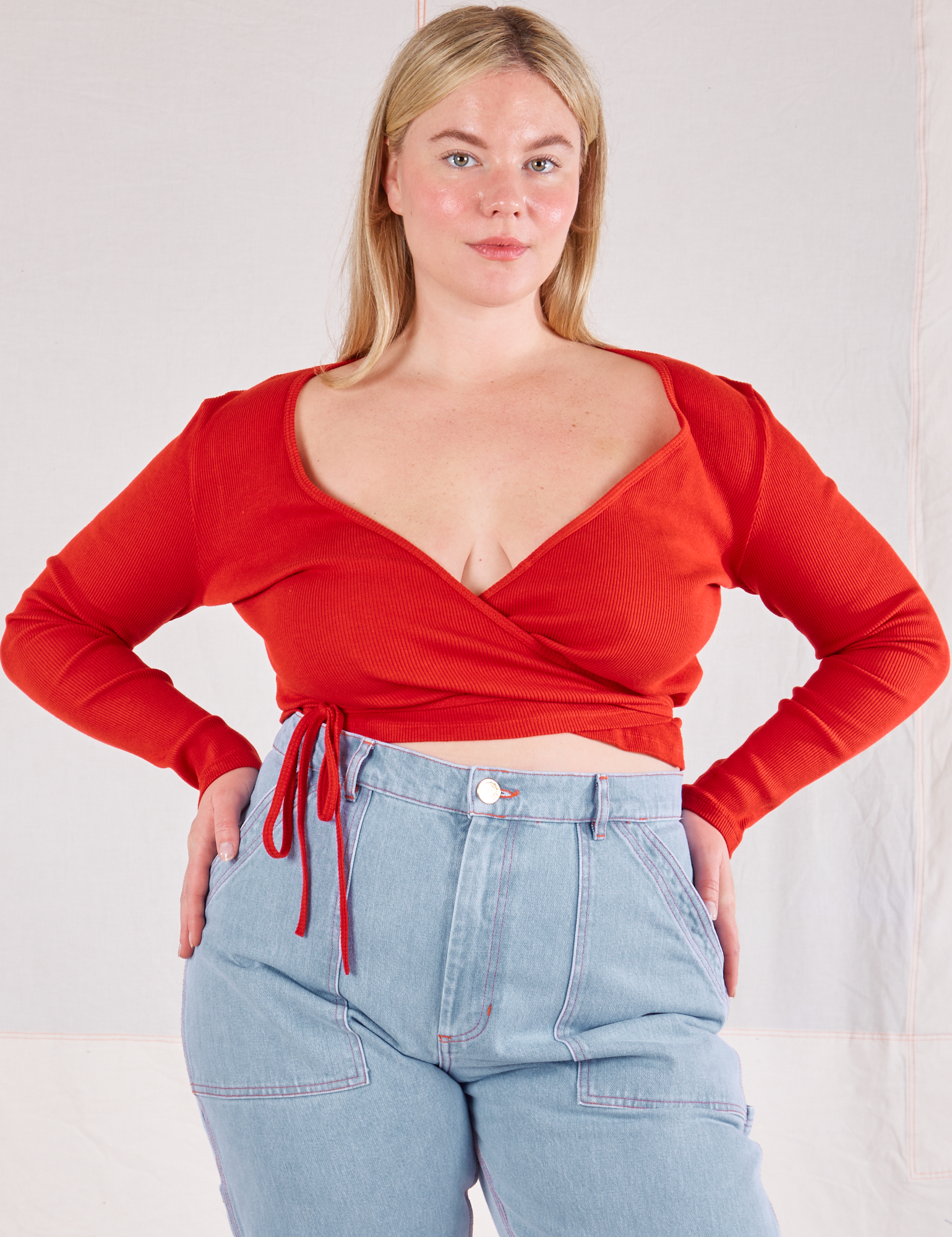 Lish is wearing Wrap Top in Mustang Red and light wash Carpenter Jeans