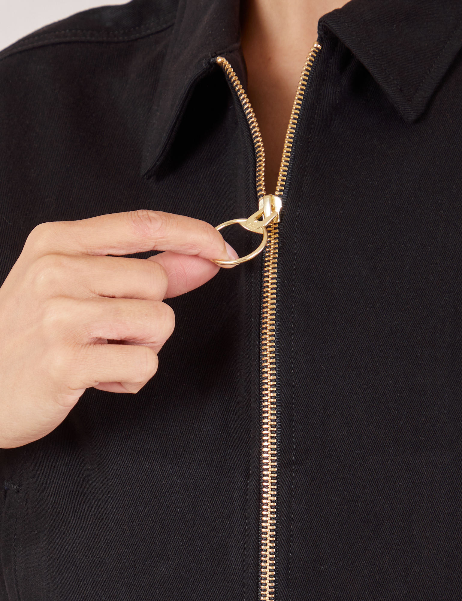 Ricky Jacket in Basic Black front close up. Tiara is pulling on the zipper pull ring