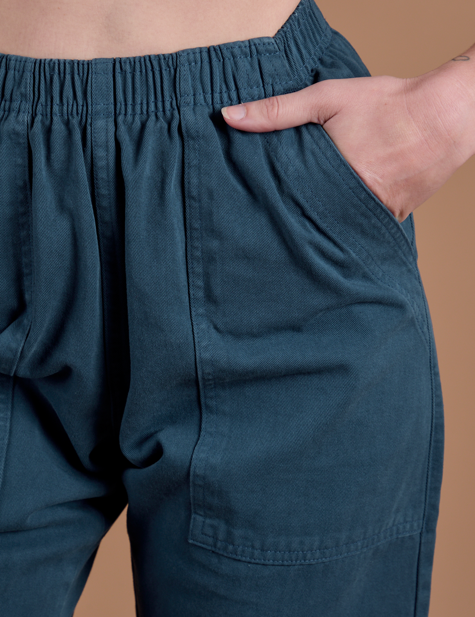 Close up of Alex's hand in the front pocket of Action Pants in Lagoon