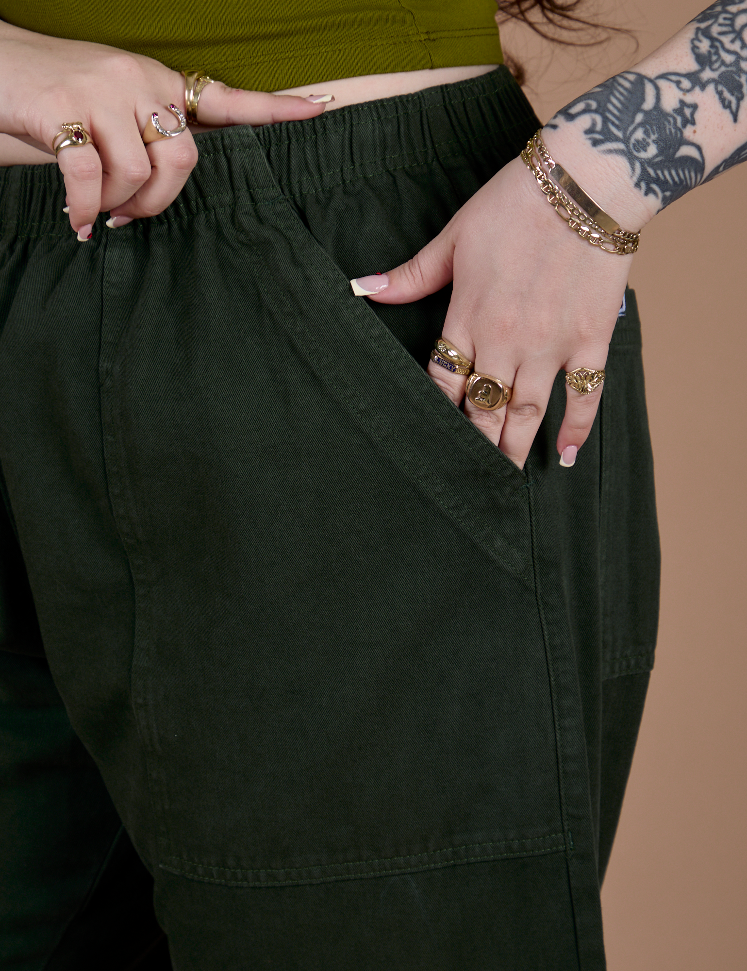 Close up of Sydney's hand in the front pocket of Action Pants in Swamp Green