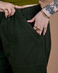 Close up of Sydney's hand in the front pocket of Action Pants in Swamp Green