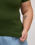 Close up of Juliet holding the Baby Tee in Evergreen bottom hem