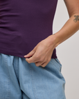 Close up of Alex holding the bottom hem of Baby Tee in Nebula Purple