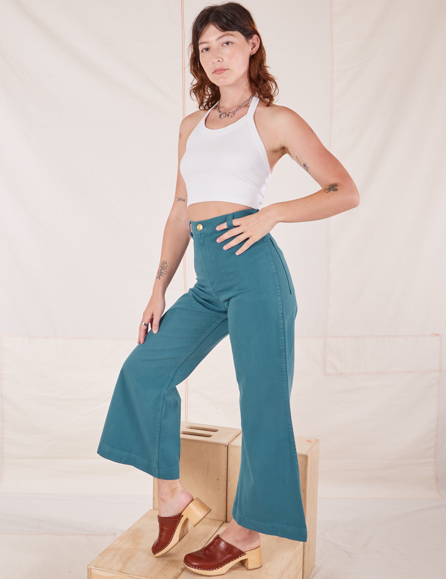 Angled view of Bell Bottoms in Marine Blue and vintage off-white Halter Top on Alex