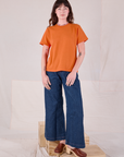 Alex is wearing Burly Tee in Construction Orange and dark wash Denim Wide Leg Trousers