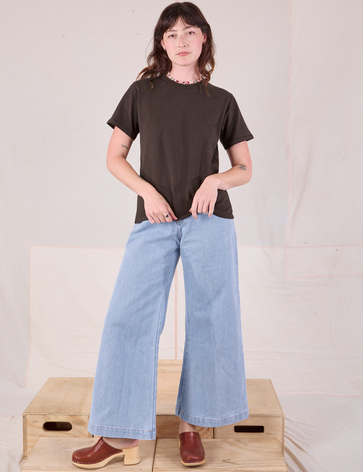 Alex is wearing Burly Tee in Espresso Brown and light wash Denim Wide Leg Trousers