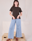 Alex is wearing Burly Tee in Espresso Brown and light wash Denim Wide Leg Trousers