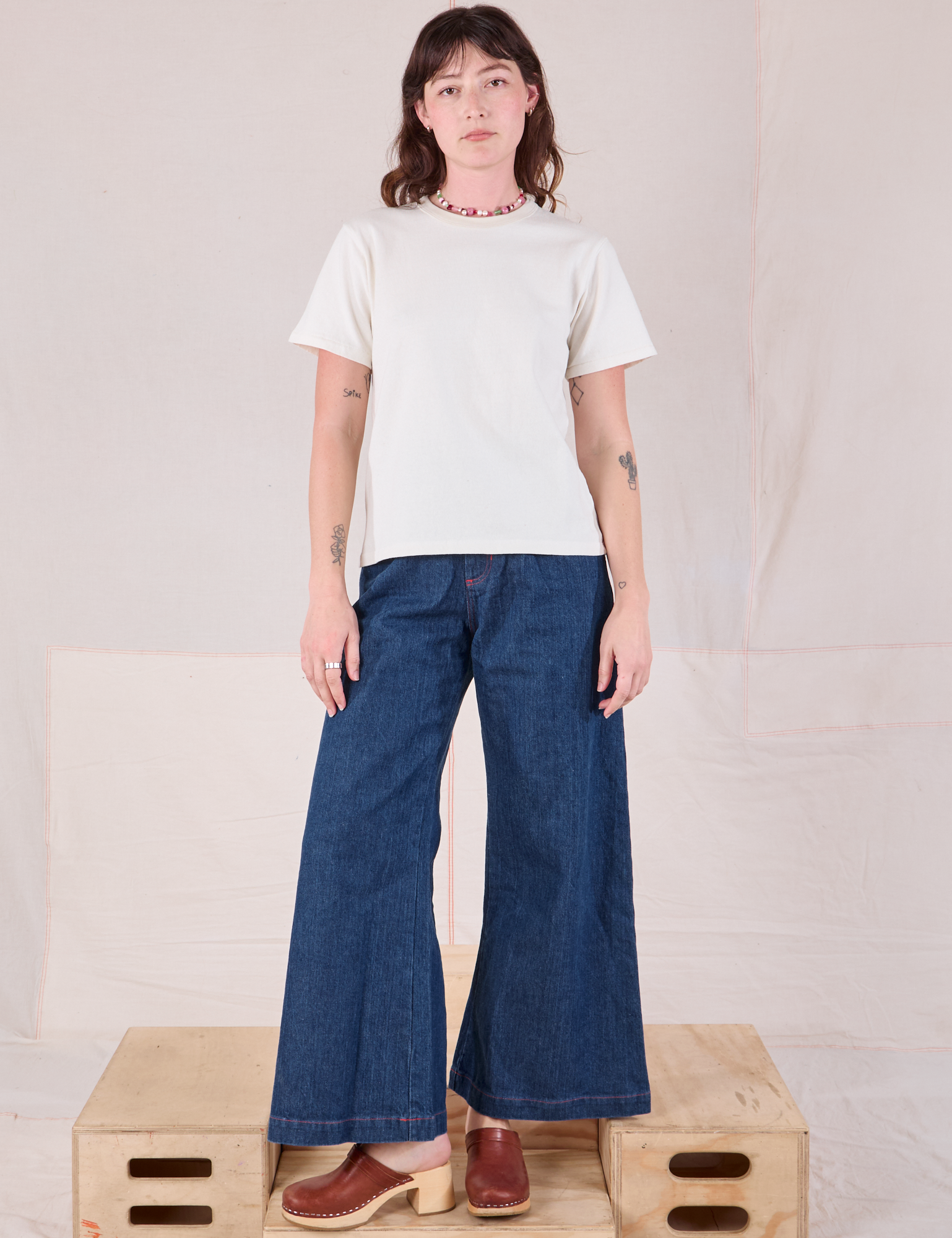 Alex is wearing Burly Tee in Vintage Tee Off-White and dark wash Denim Wide Leg Trousers