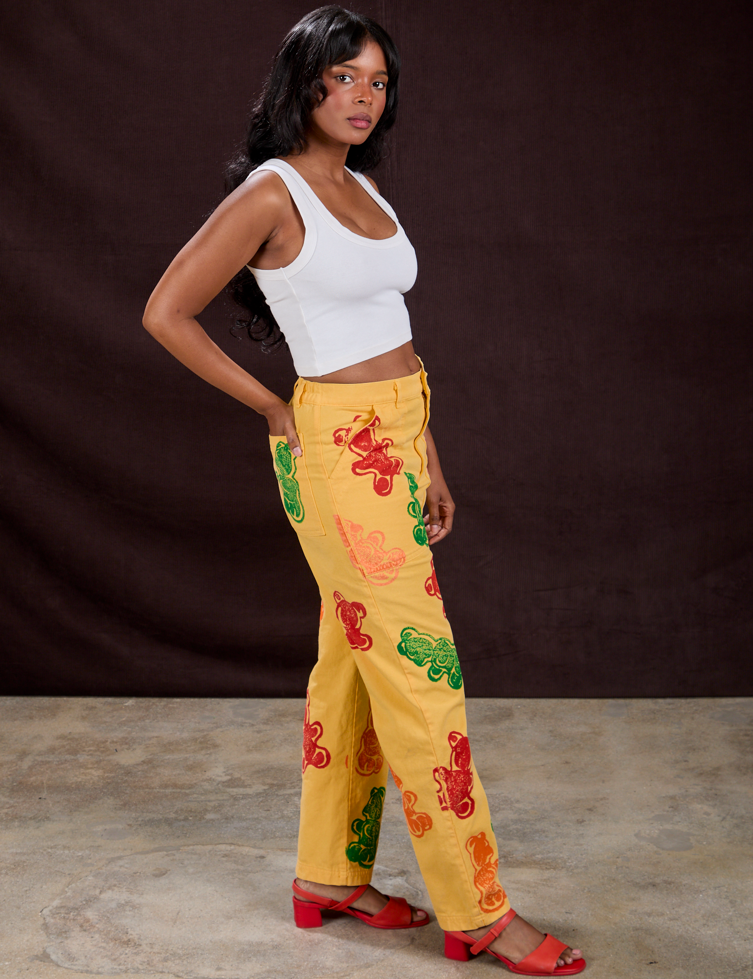 Side view of Gummy Bear Paintstamped Work Pants in Butter Yellow and Cropped Tank in Vintage Tee White