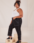 Side view of Carpenter Jeans in Black and vintage off-white Tank Top worn by Morgan