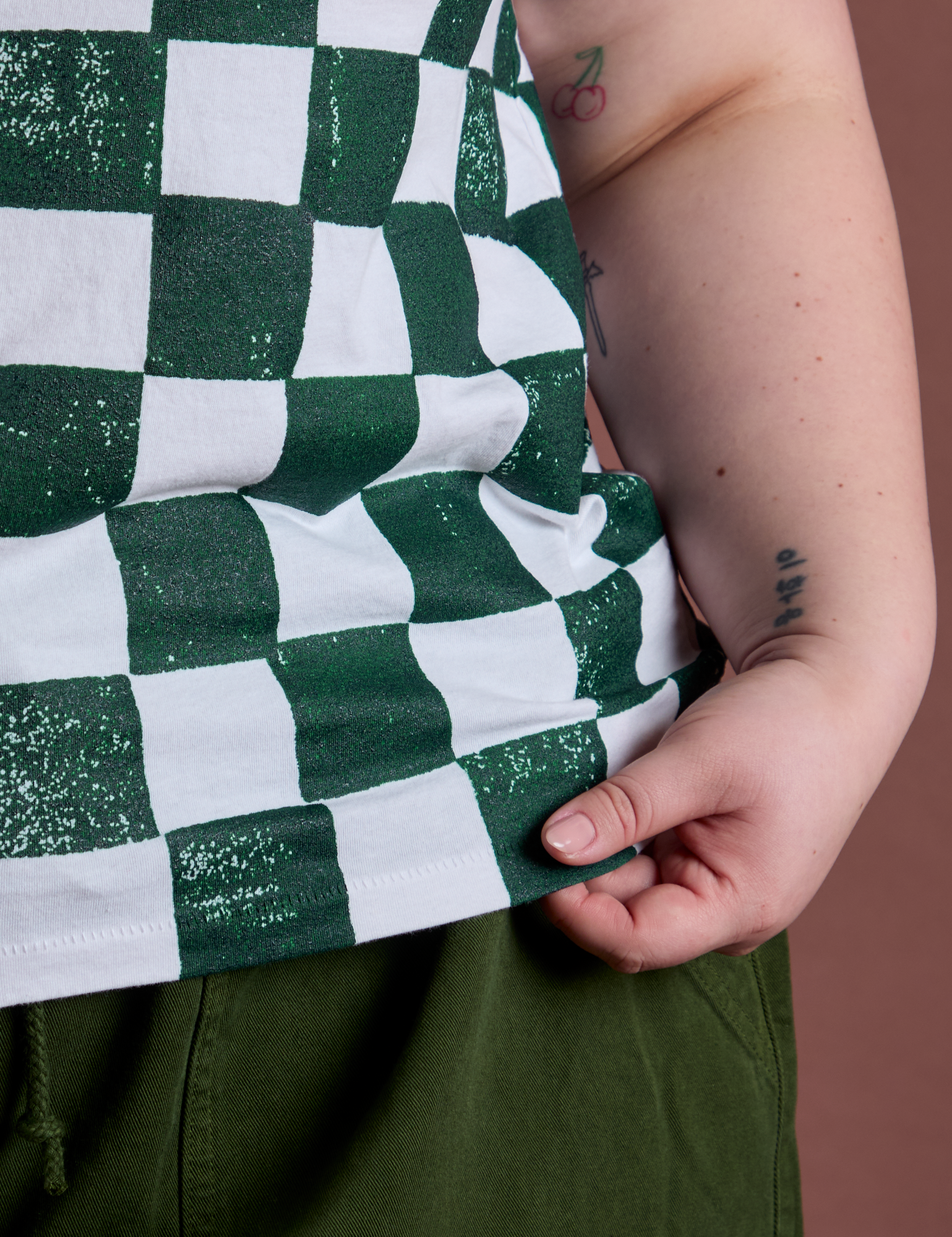 Checker Organic Tee in Swamp Green bottom close up with Ashley holding the hem
