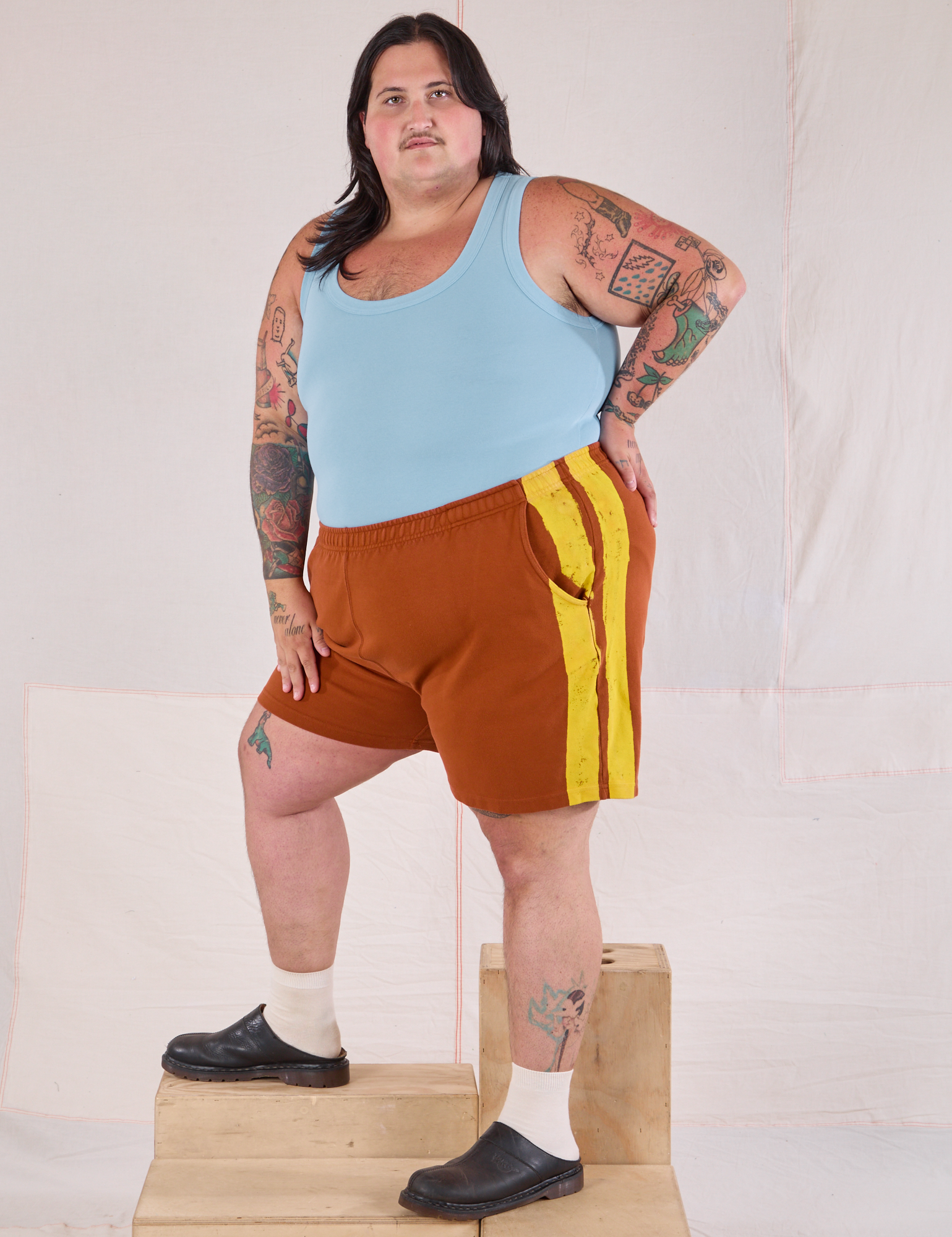 Angled view of Painted Stripe Easy Shorts in Burnt Terracotta and baby blue Tank Top on Sam