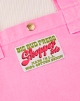 Shopper Tote Bag in Bubblegum Pink. Close up of brass sun baby snap and bag label with green and pink text on a white background