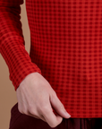 Bottom close up of Gingham Long Sleeve Baby Tee in Mustang Red with Alex holding the hem