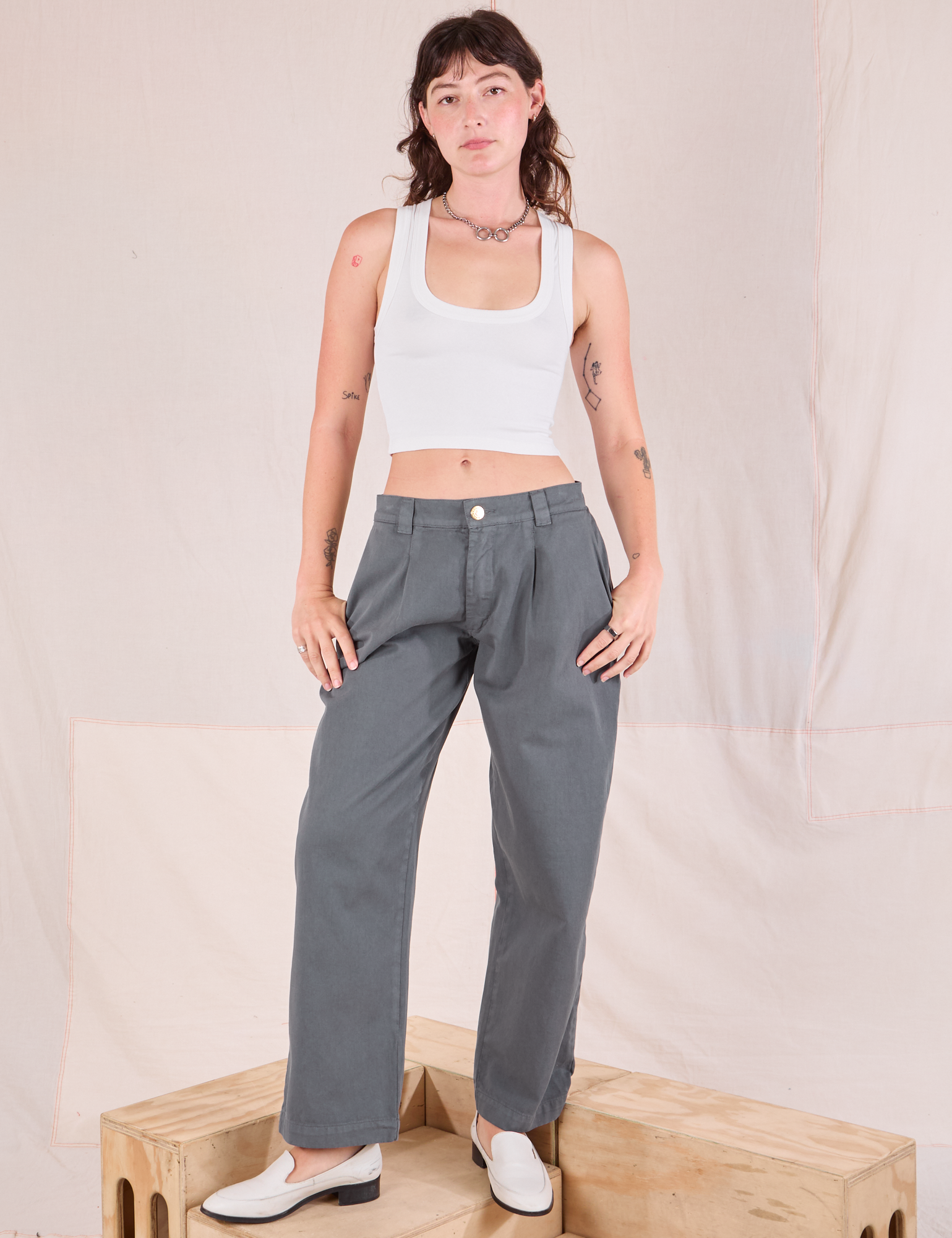 Alex is wearing Mid-Rise Pleated Trousers in Slate Grey and Cropped Tank in vintage tee off-white