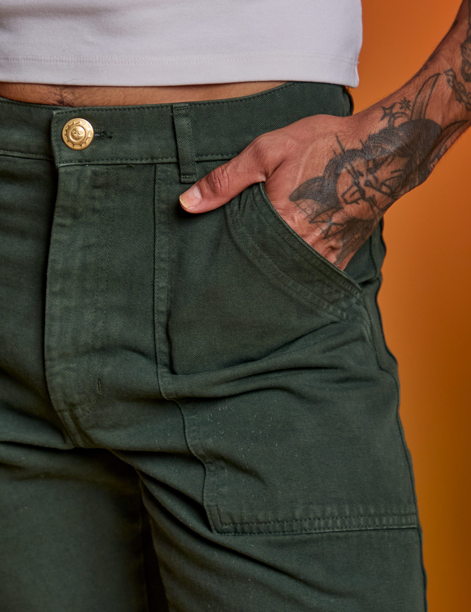 Close up of Jesse&#39;s hand in the front pocket of Paintstamped Work Pants in Cactus